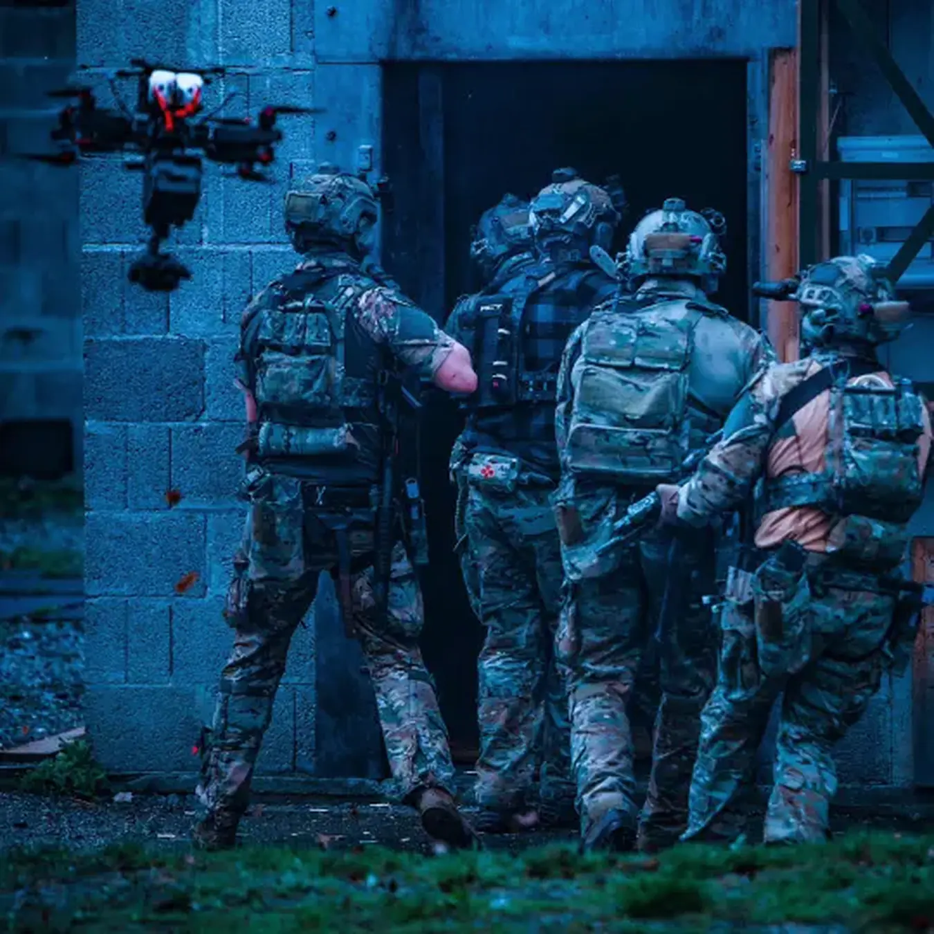 Staged tactical film team entering a doorway on set